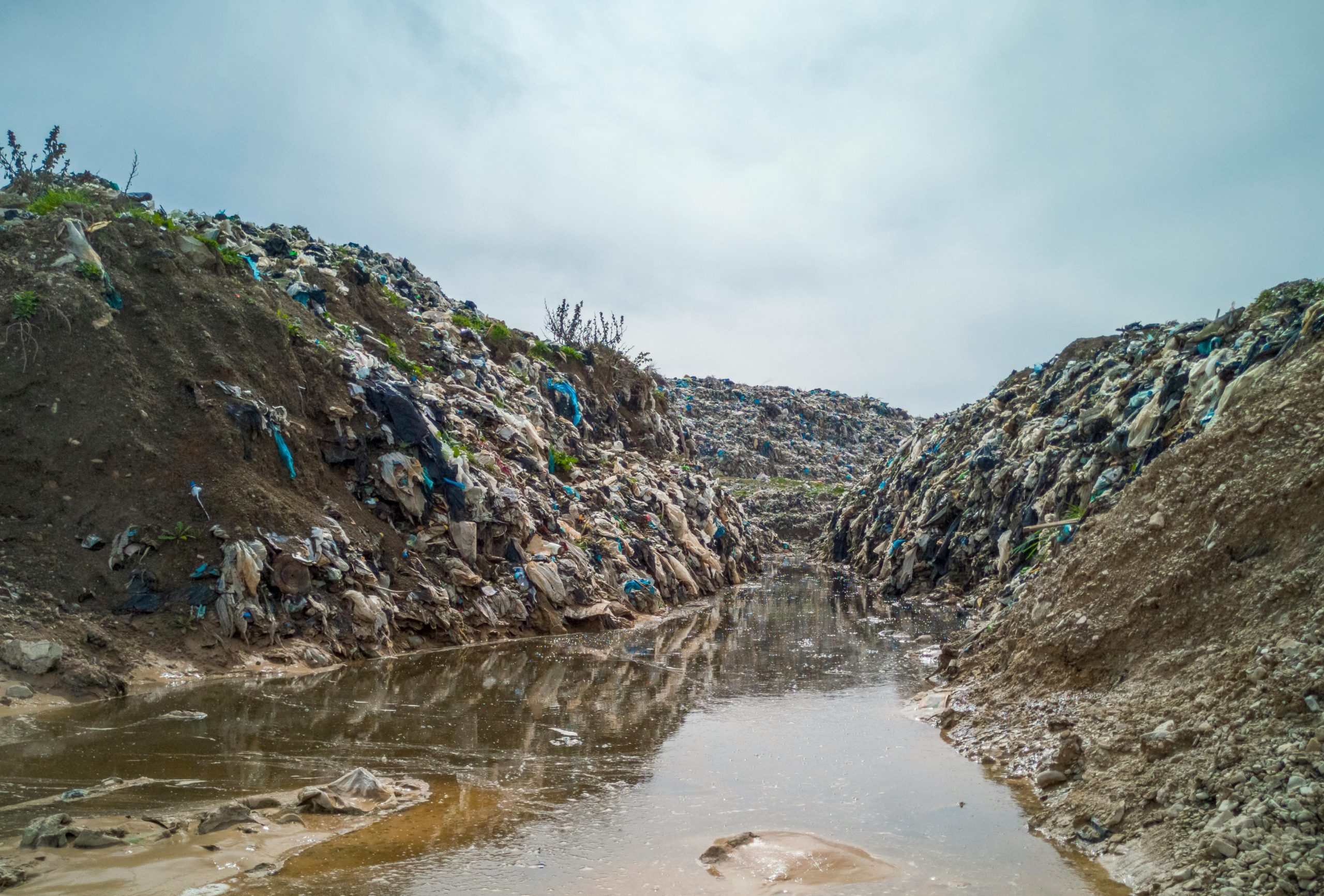 Image of mounds of rubbish by and in a river.